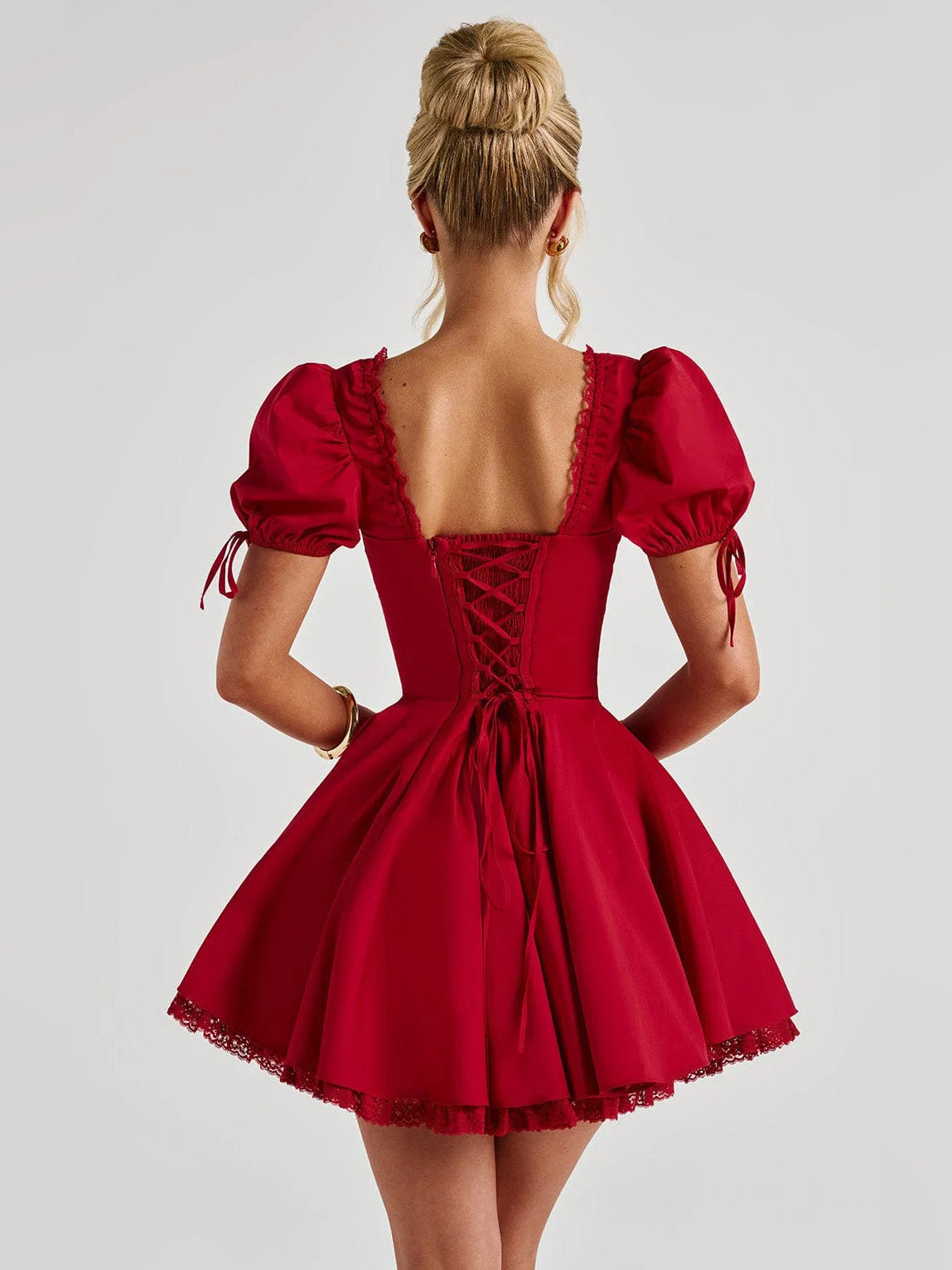 Back view of red mini dress with corset-style open back, puff sleeves, flared skirt