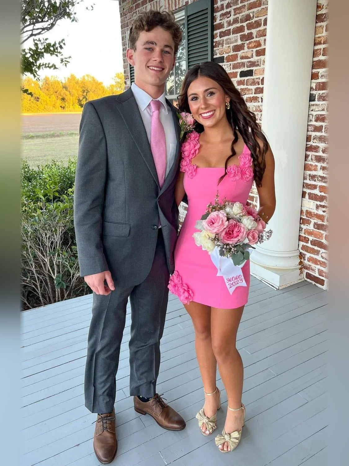 Pink mini sheath dress with square neckline and floral rosette appliques, worn with heels