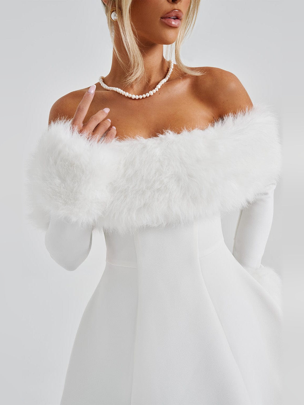 Ivory mini dress neckline with pearl-like trim and off-shoulder faux fur sleeves.