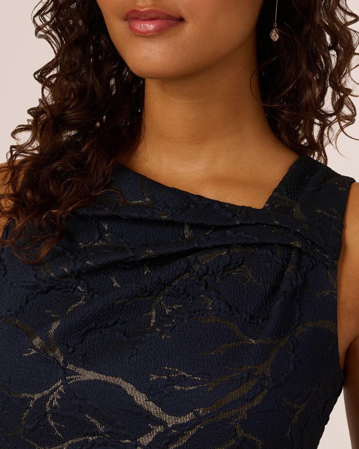 Navy sleeveless dress neckline with layered drape and gold abstract textured pattern