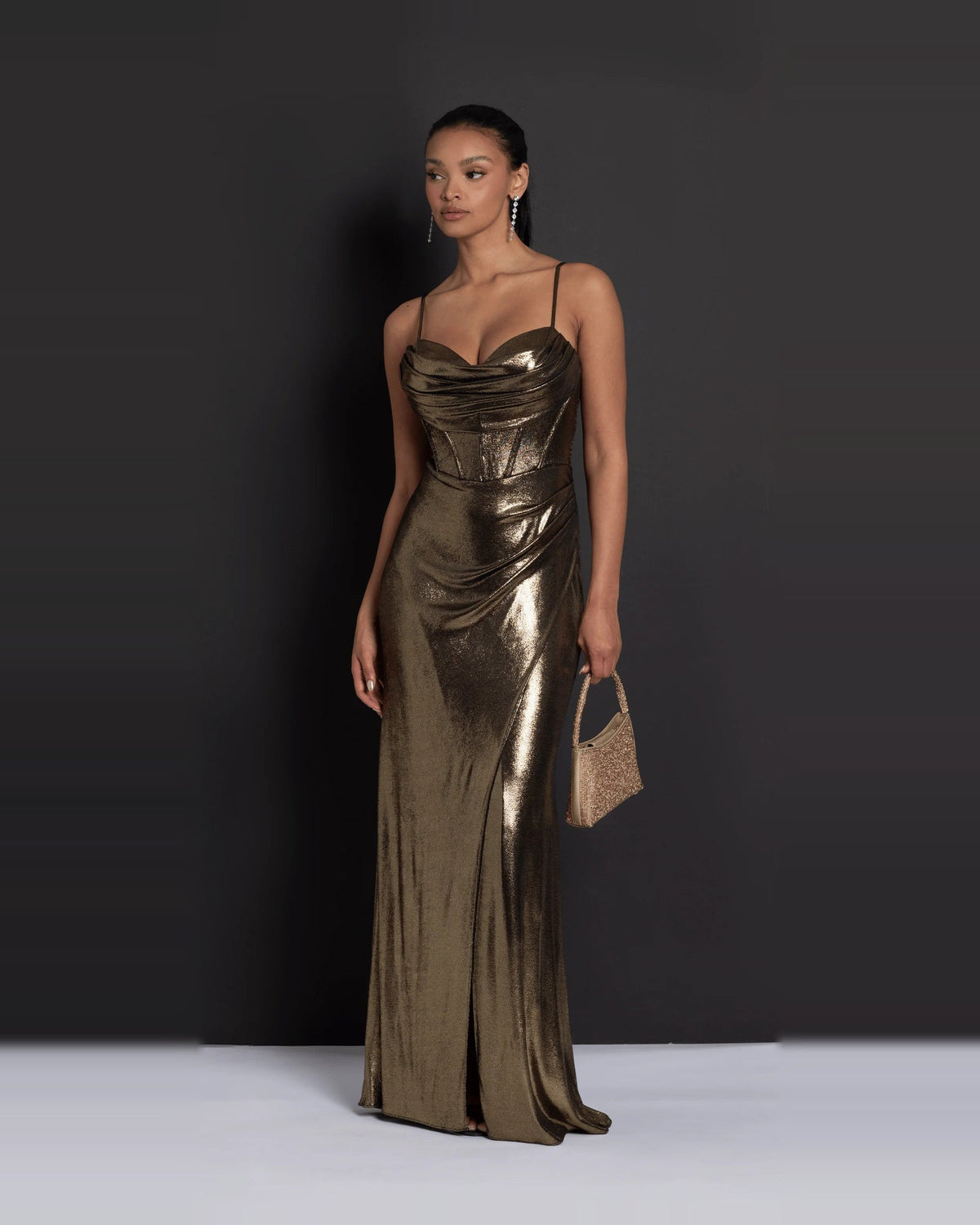 Gold ruched sweetheart maxi dress with draped bodice, styled with a small clutch