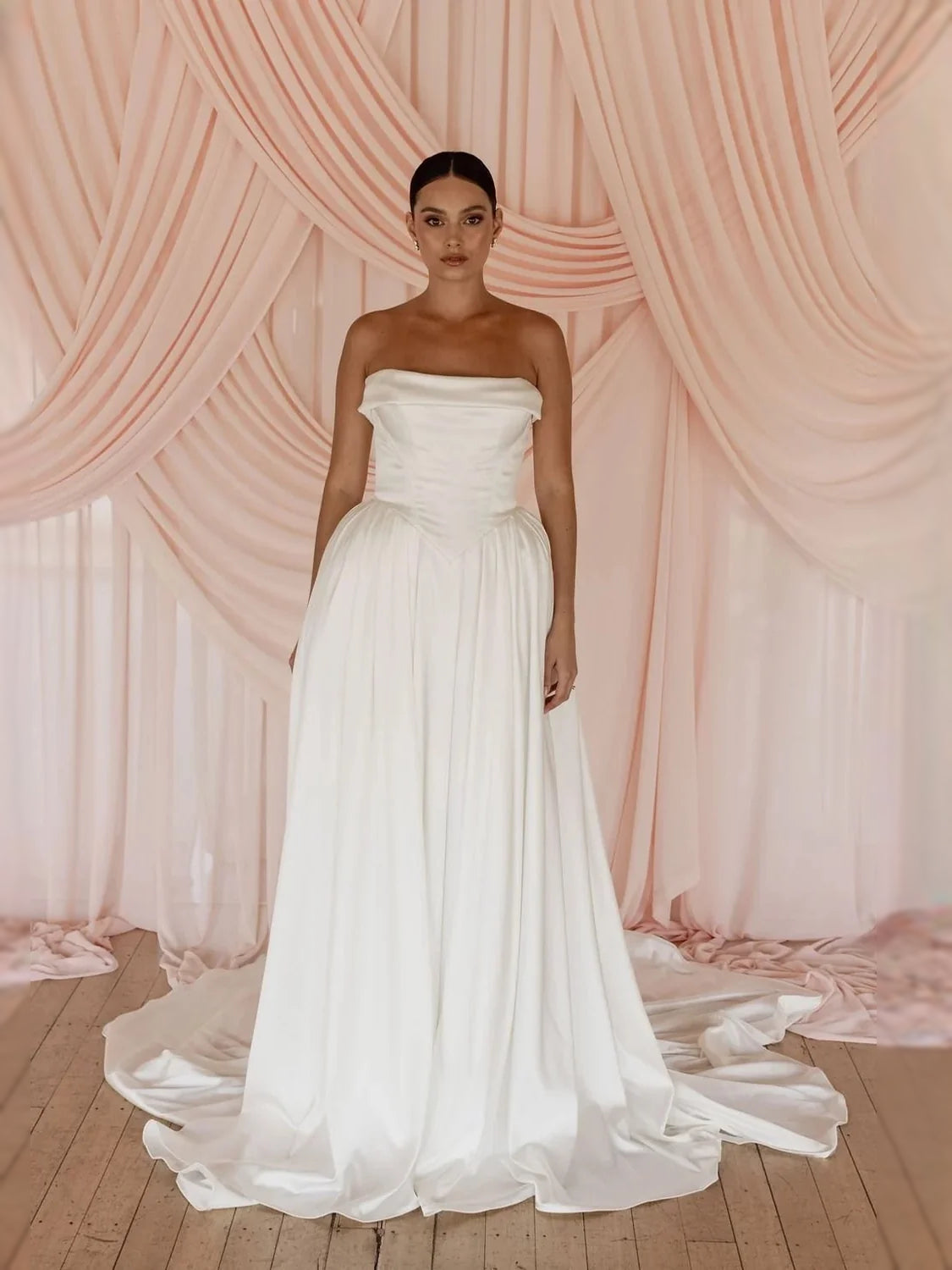 Ivory off-shoulder satin ball-gown wedding dress with gathered waist and flowing skirt