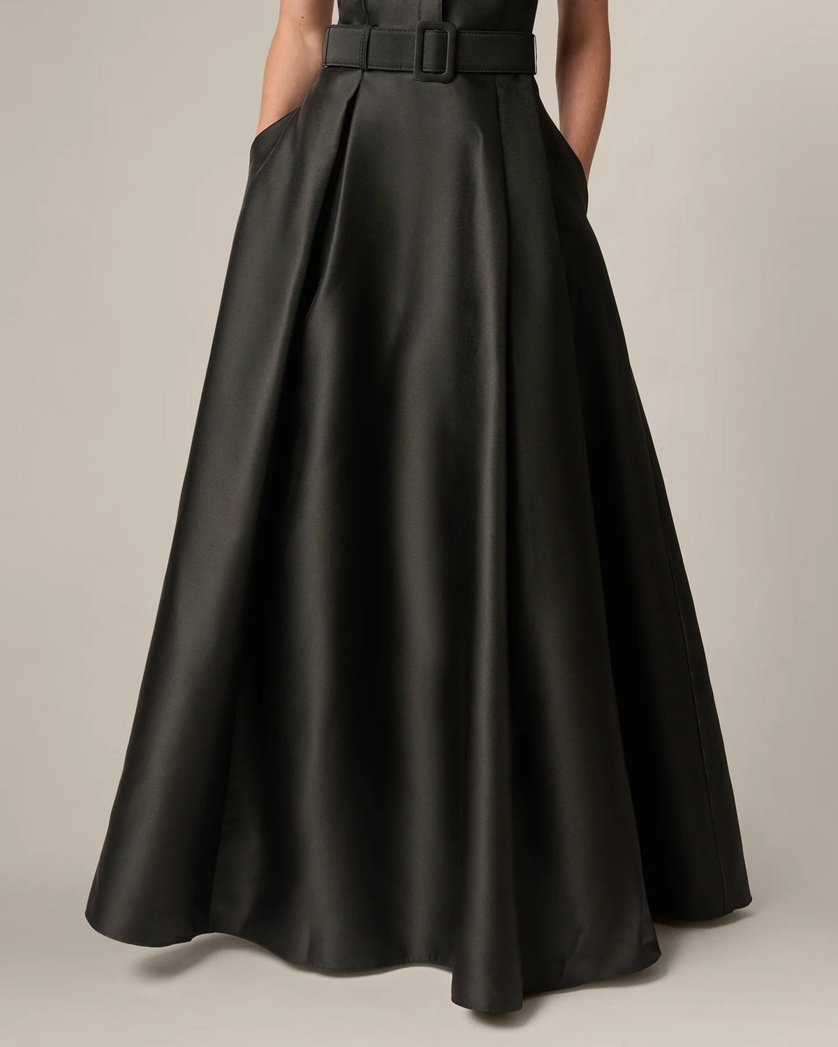 Black A-line maxi skirt with belt at waist, draped fabric close-up