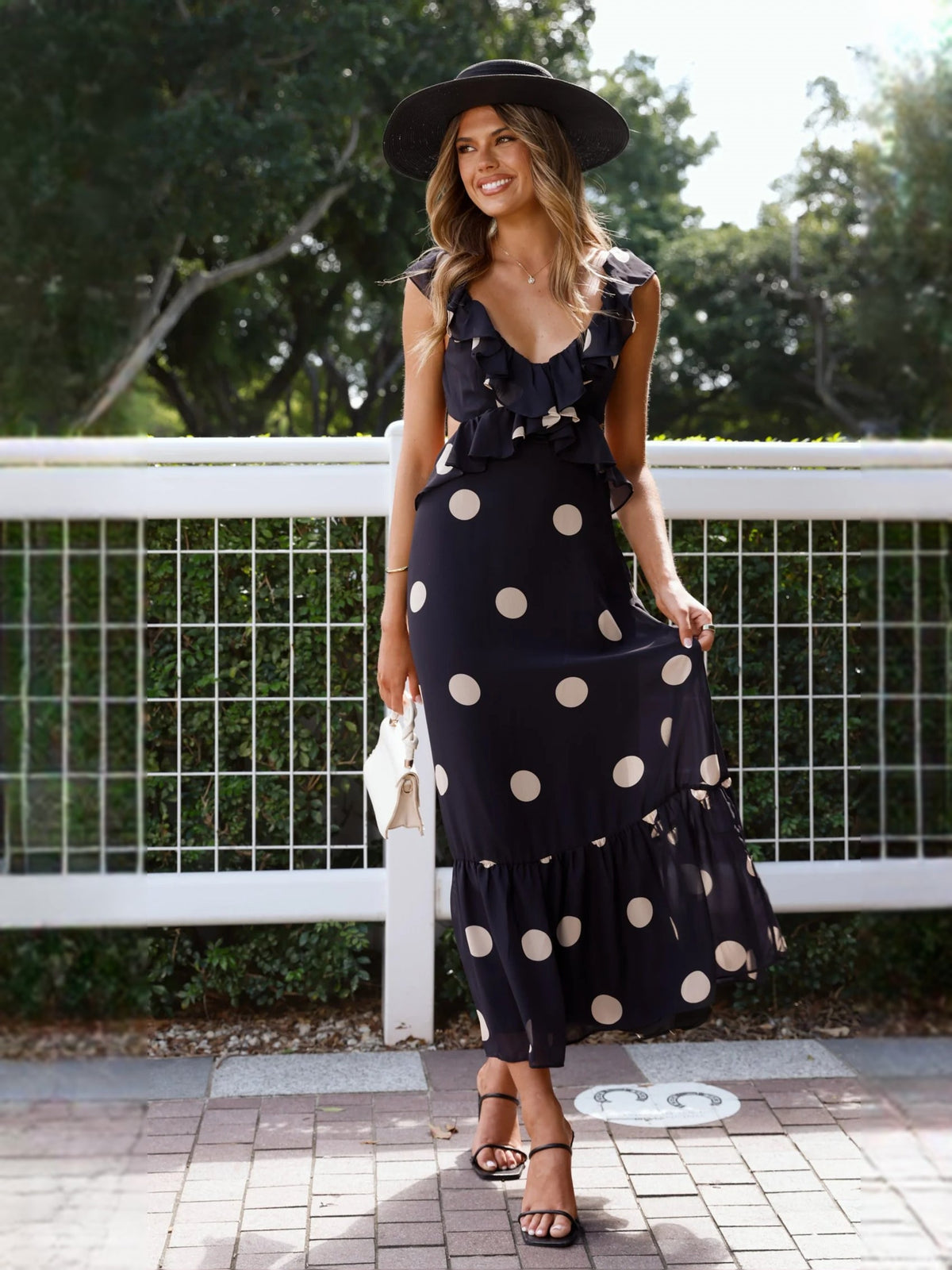 Black polka-dot midi dress with layered ruffle neckline and flowing tiered hem