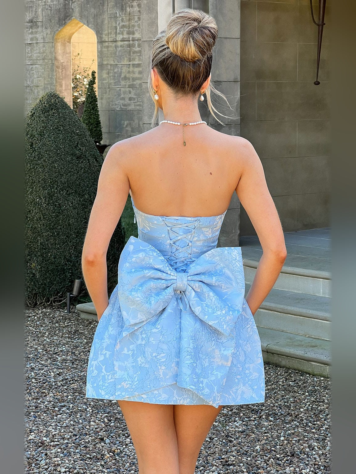 Back view of blue strapless mini dress with corset lacing and large waist bow.