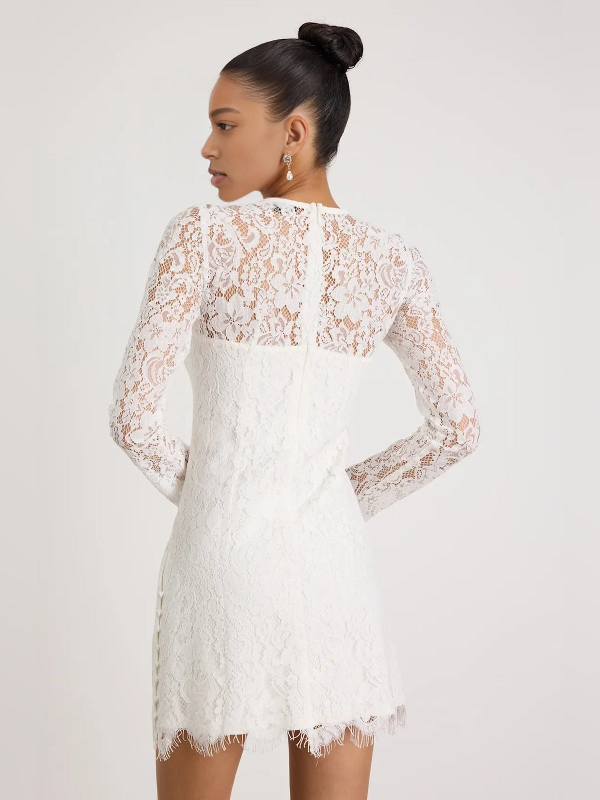 White lace mini homecoming dress with long sleeves, round neckline, and fringe hem