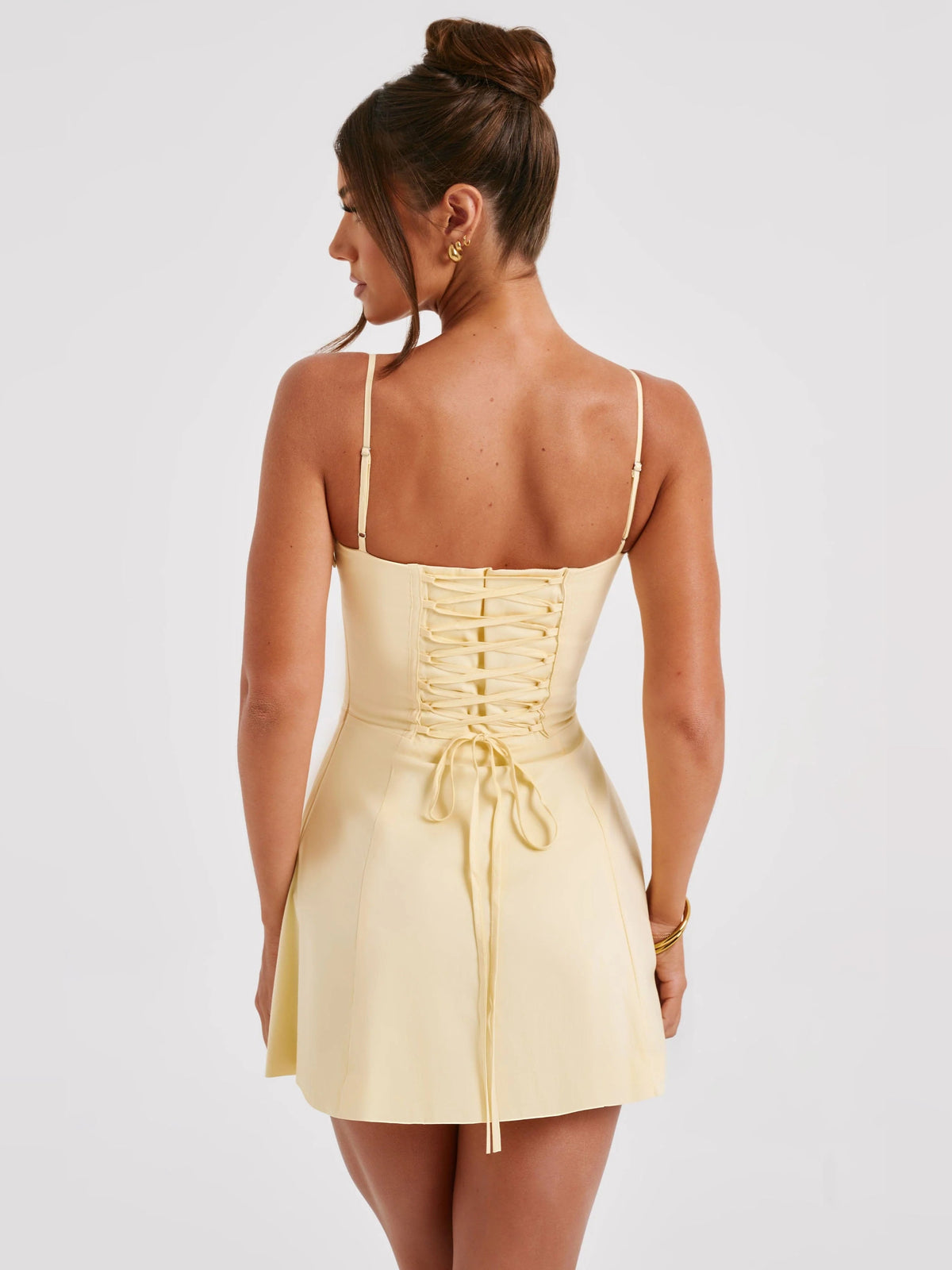 Back view of lemon mini dress with lace-up corset back and tied waist