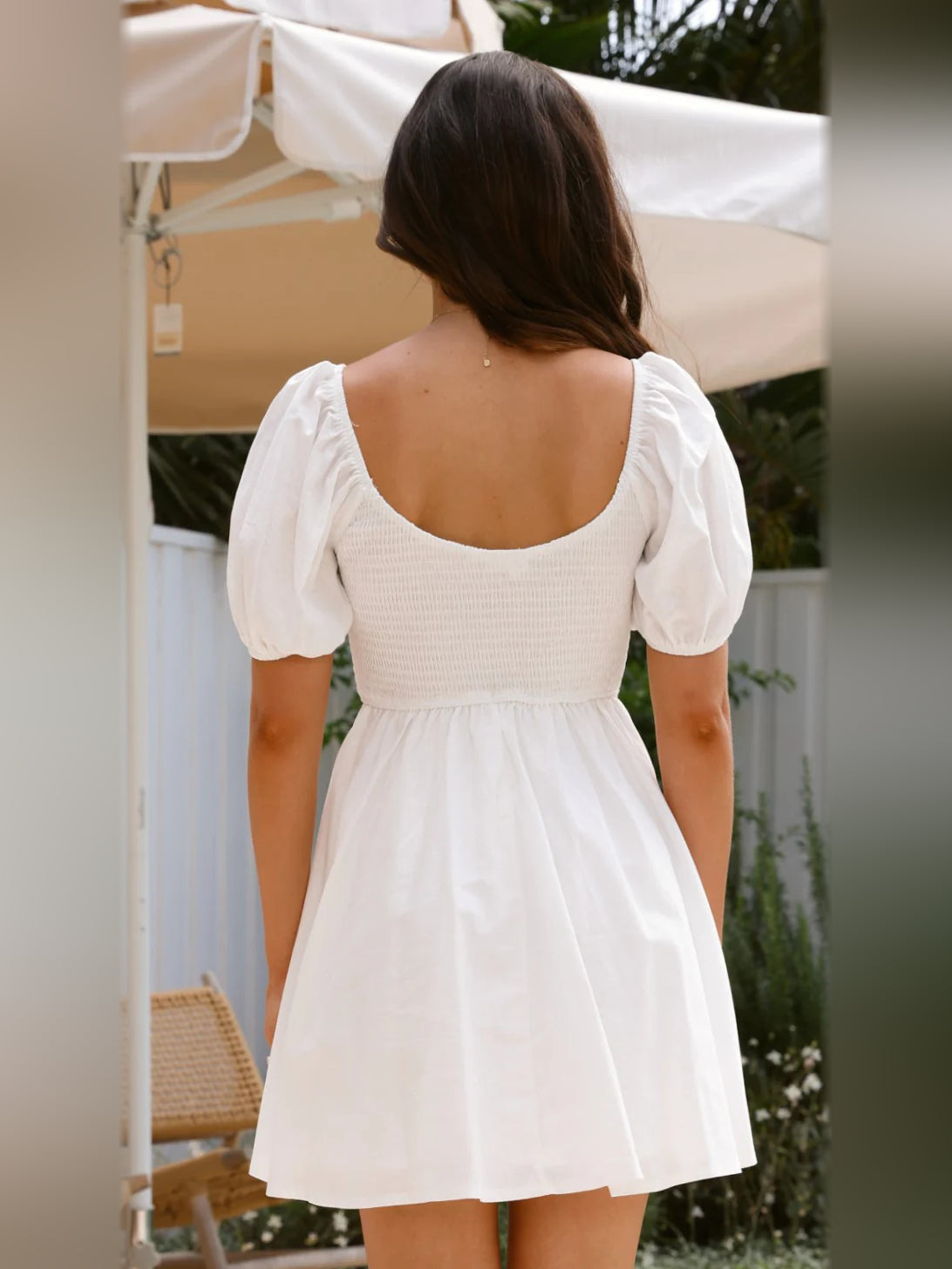 White mini homecoming dress from back view with puff sleeves and gathered waist