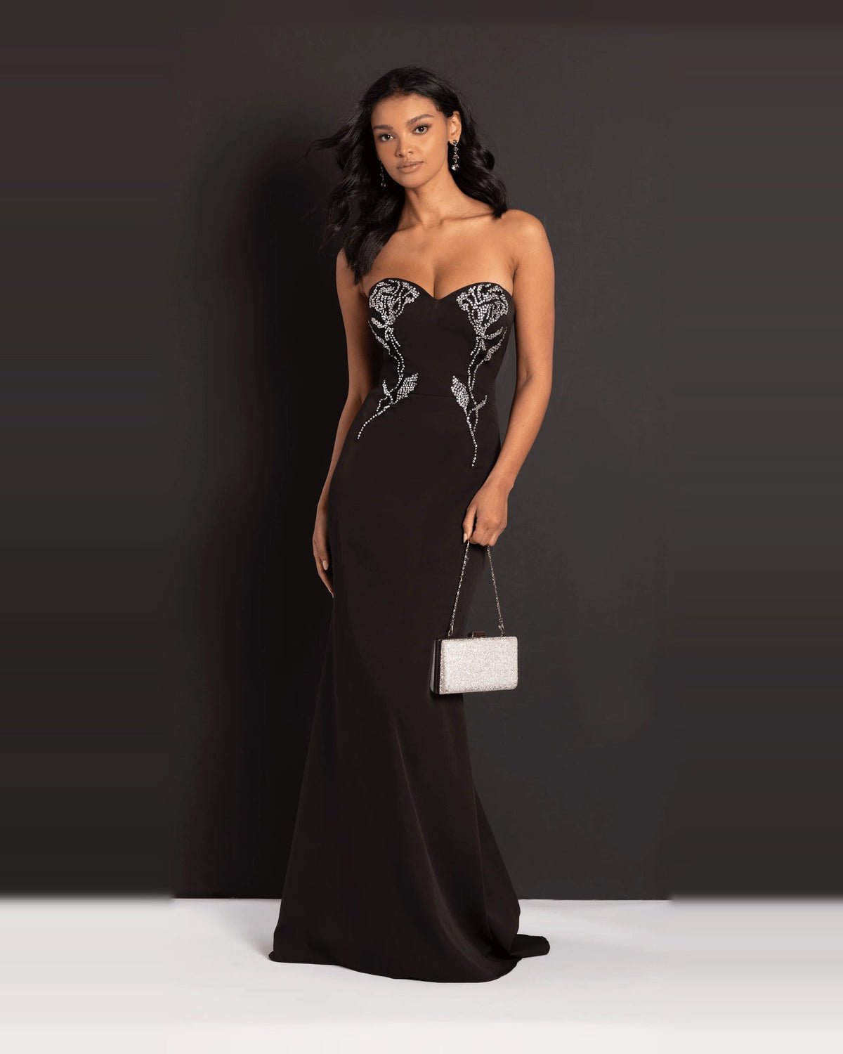 Black strapless trumpet maxi prom dress with rhinestone bodice and glitter clutch