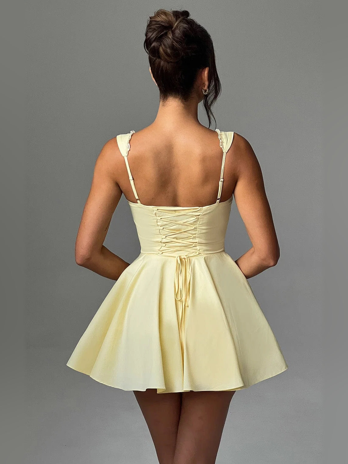 Back view of lemon yellow mini dress with thin shoulder straps and flared skirt