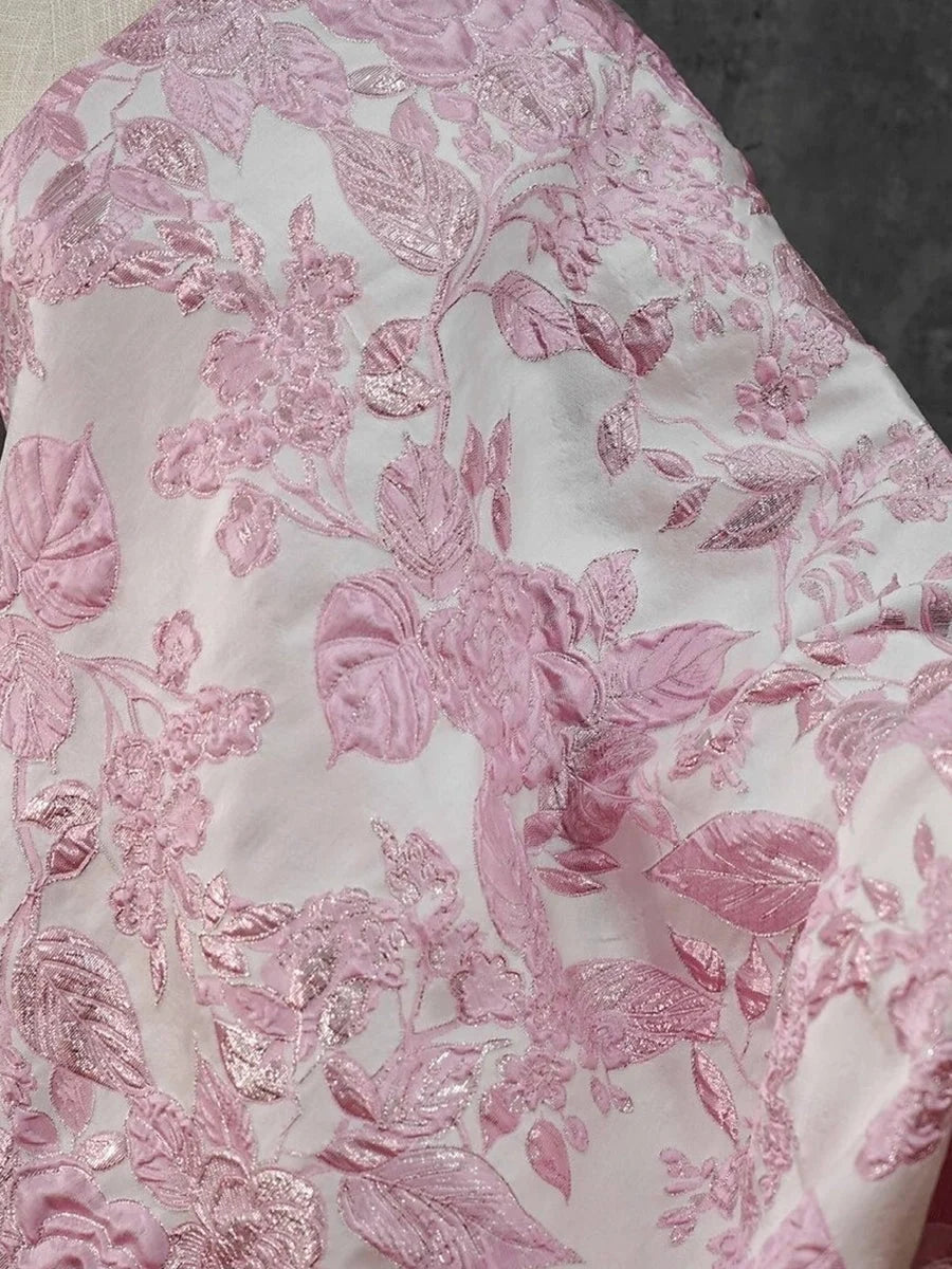 Close-up: pink floral textured embroidery on light fabric