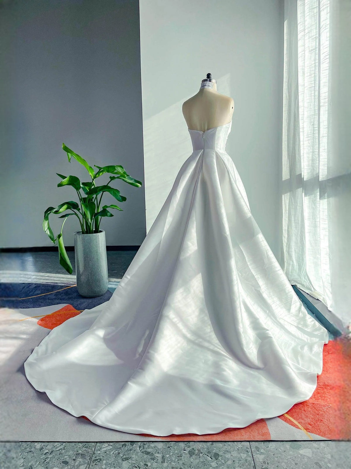 White strapless sweetheart A-line satin wedding dress with full flowing skirt, back view