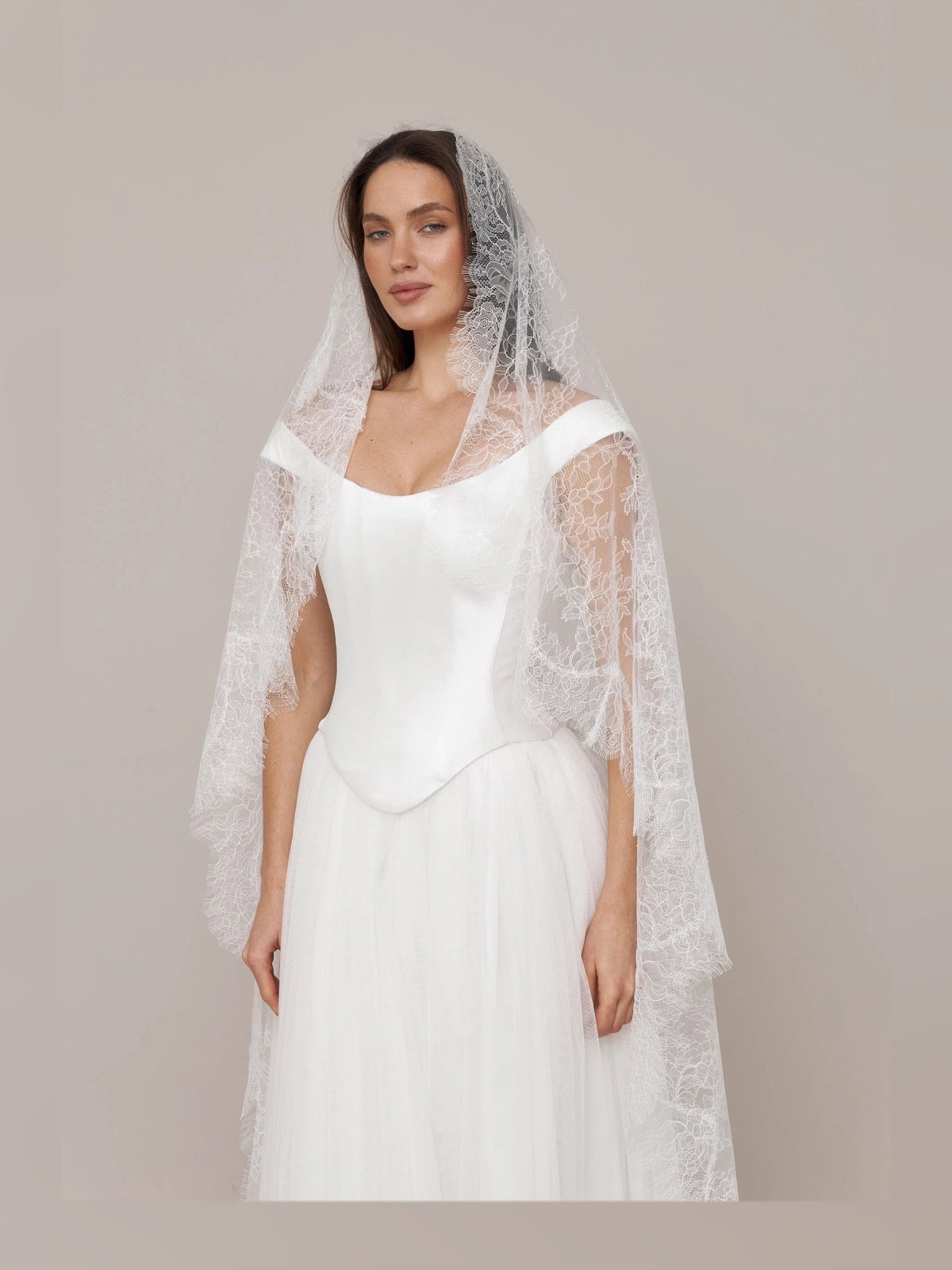 Ivory off-shoulder satin wedding dress with corset bodice and lace veil detail