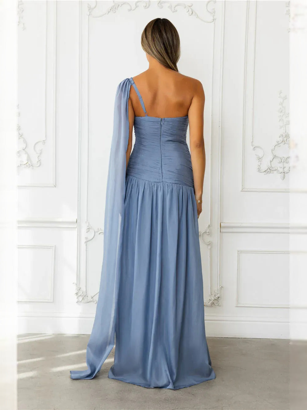 Ruched one-shoulder maxi dress in dusty blue, back view with open strap and flowing skirt