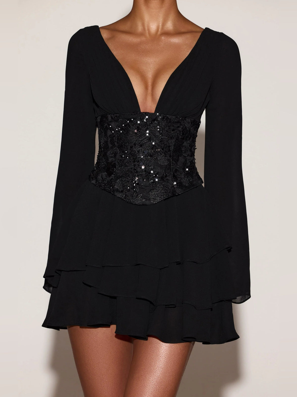 Black long-sleeve corset mini dress with sequin bodice, deep V-neck, layered ruffle hem