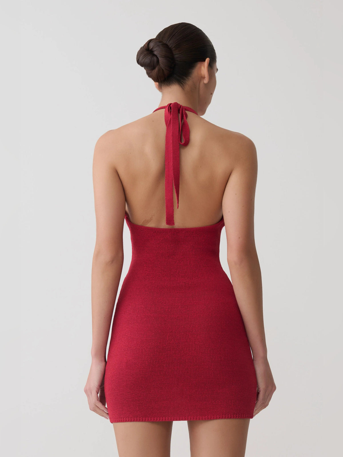 Back view of pomegranate halter-neck mini dress with tied strap and open back