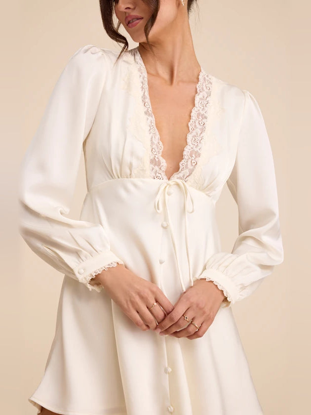 Ivory satin mini dress with lace V-neck trim, long sleeves, and front tie