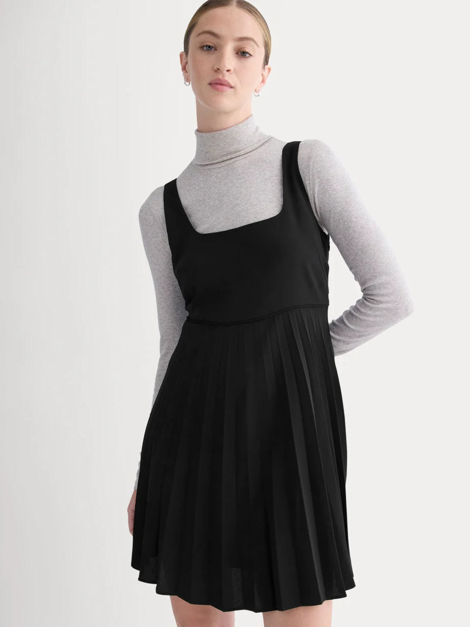 Black sleeveless mini dress with scoop neckline and pleated skirt, front angled