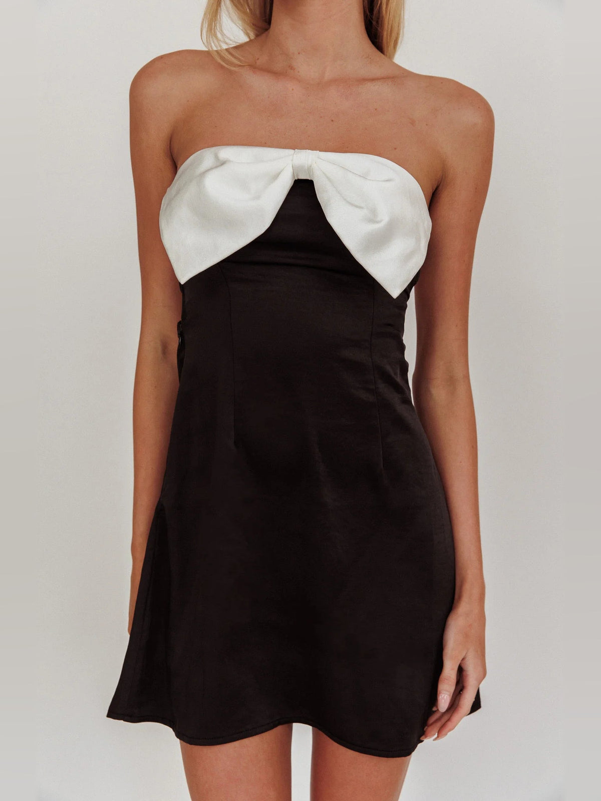 Black strapless mini dress with white bow applique at the neckline