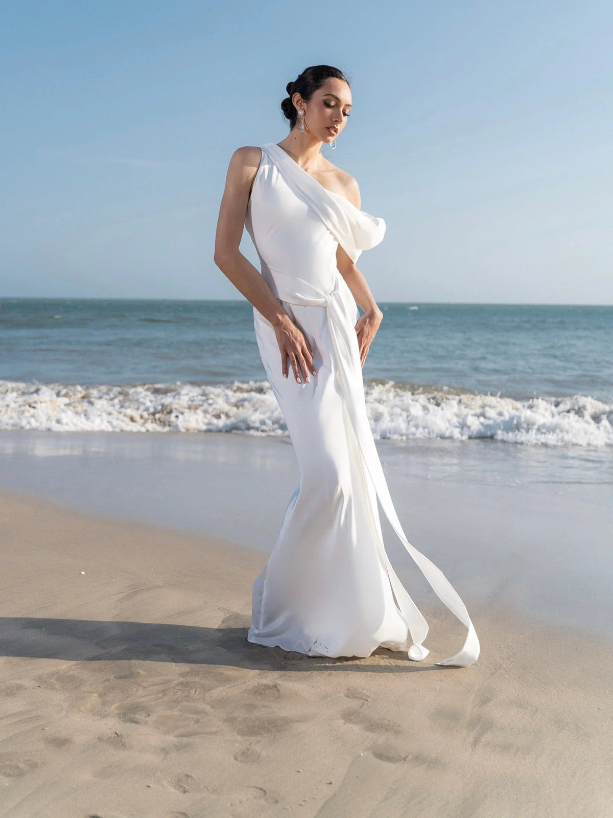 White satin sheath midi wedding dress with one-shoulder drape and flowing cowl detail