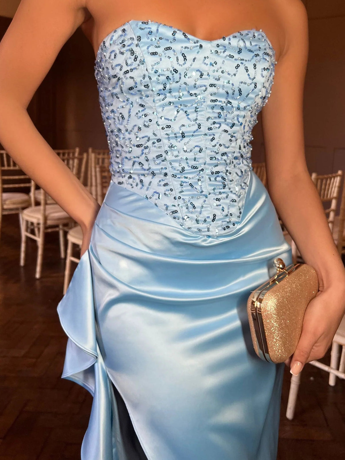 Close-up of blue strapless ruched bodice with jeweled pattern and draped satin skirt