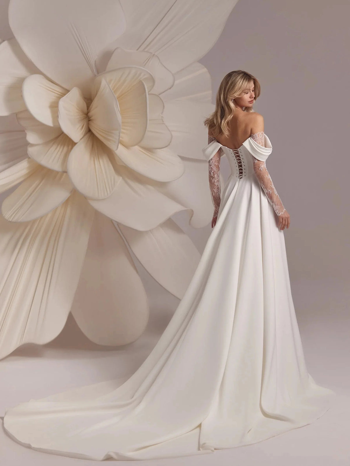 Ivory off-shoulder satin wedding gown with corset bodice, lace sleeves, and long skirt