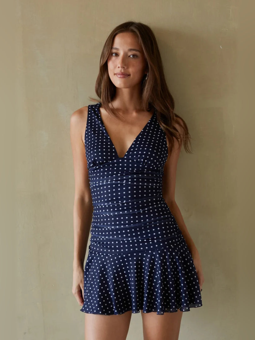 Navy mini homecoming dress with V-neck, sleeveless bodice, and white dotted flared skirt