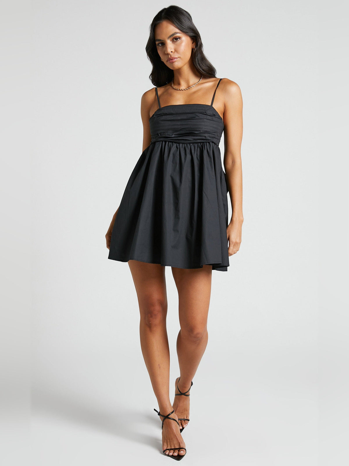 Black mini dress with ruched bust, spaghetti straps, and gathered skirt