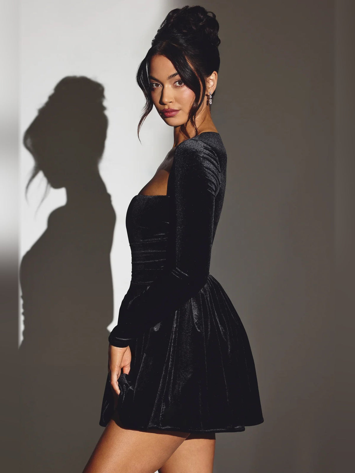 Black velvet corset mini dress with long sleeves and flared skirt, side view