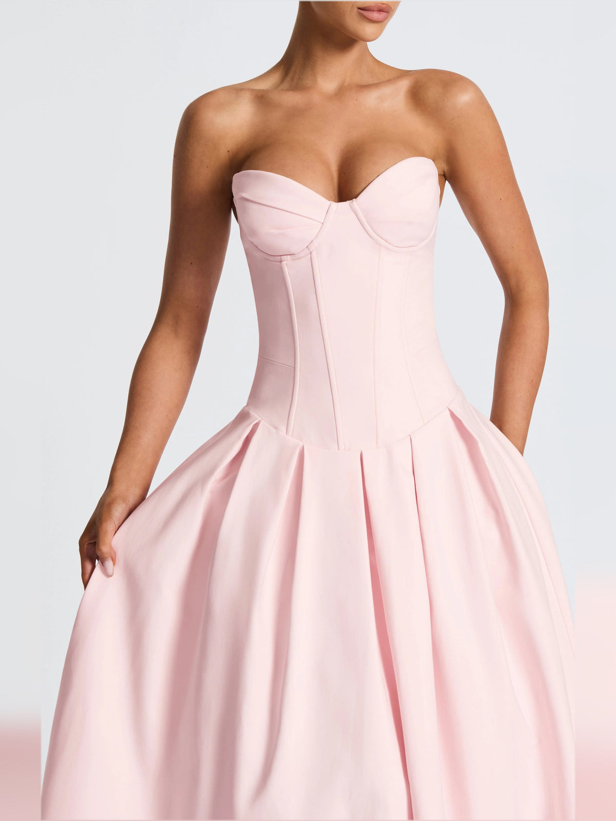 Blush pink strapless corset-style midi dress with sweetheart neckline and pleated skirt