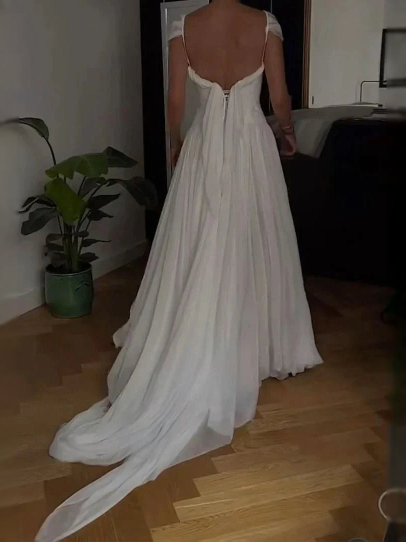Ivory A-line wedding dress viewed from behind, pleated chiffon skirt and thin straps