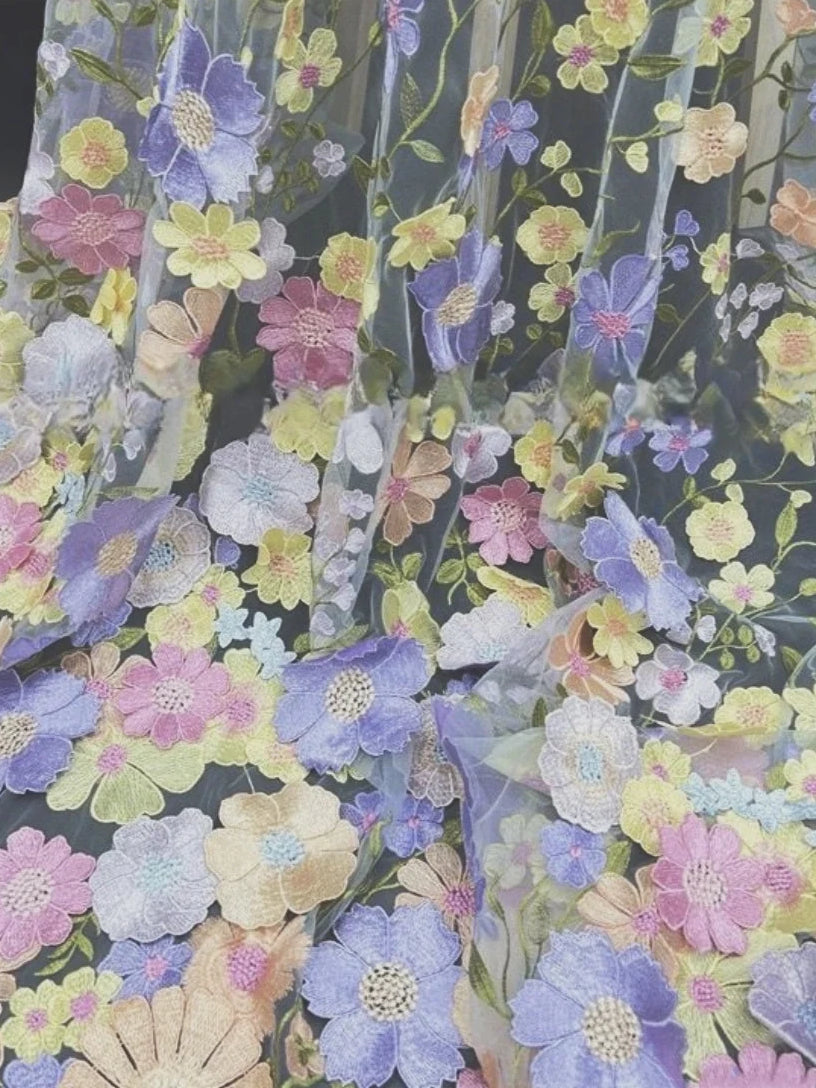 Light blue tulle with multicolor floral embroidery close-up fabric texture