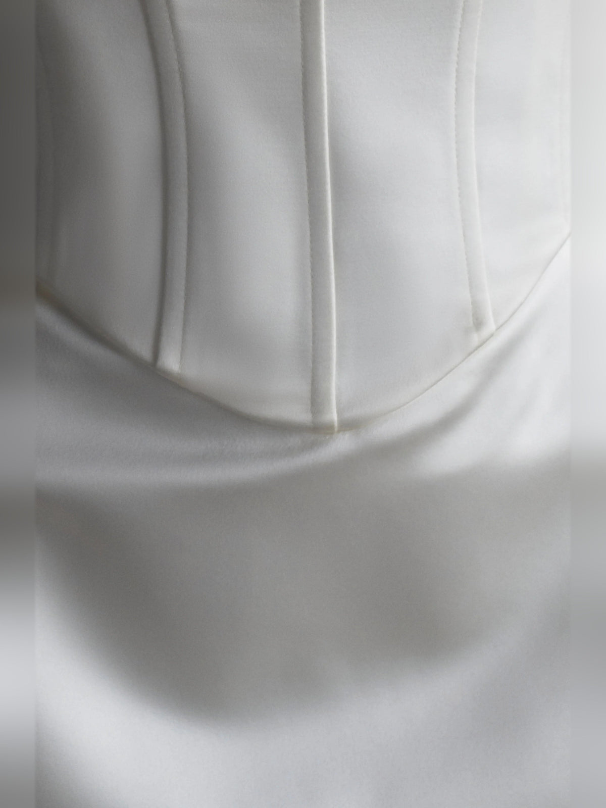 White satin corset bodice close-up with vertical seam detailing
