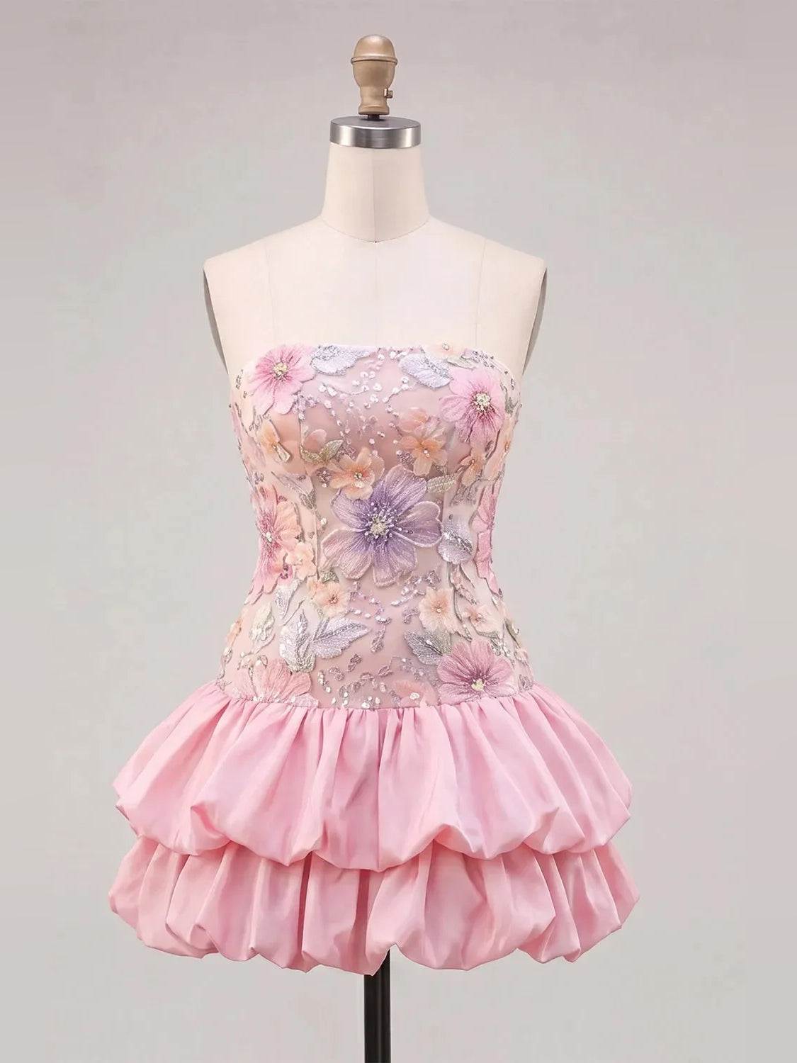 Pink floral strapless mini dress on mannequin with embellished bodice and ruffled skirt