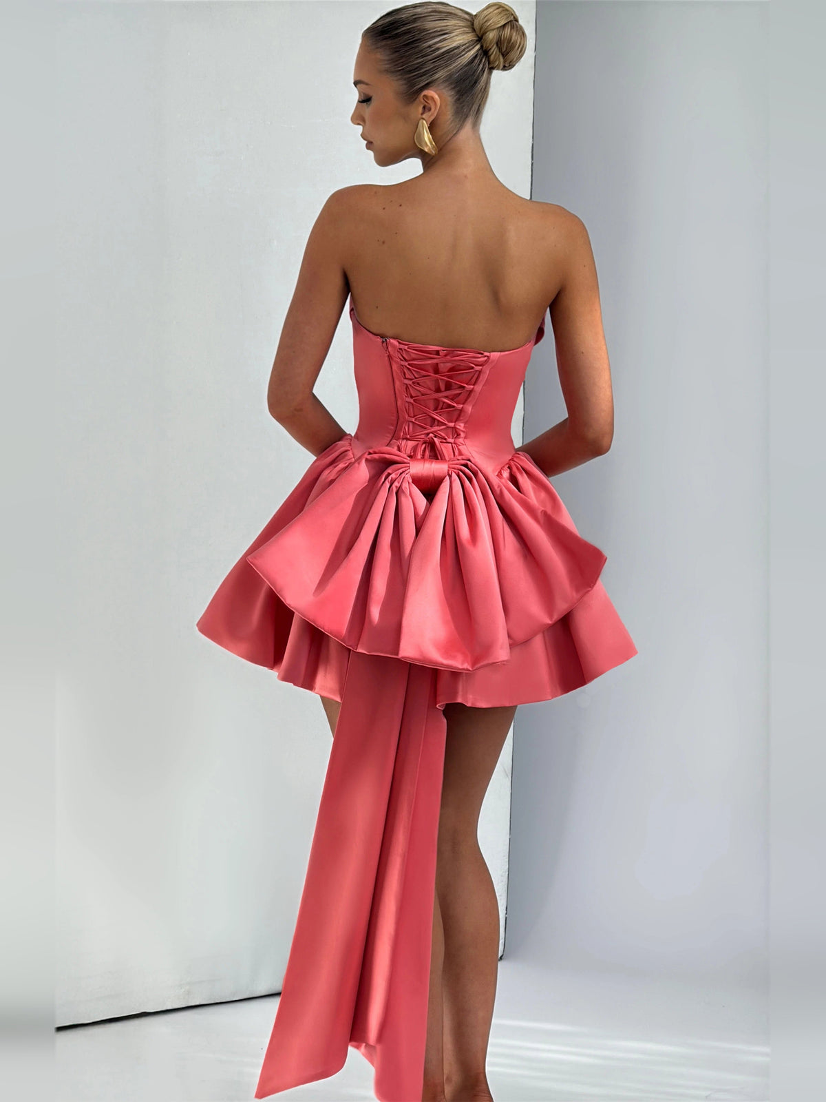 Pink backless mini dress with corset lace-up back and layered peplum-style skirt