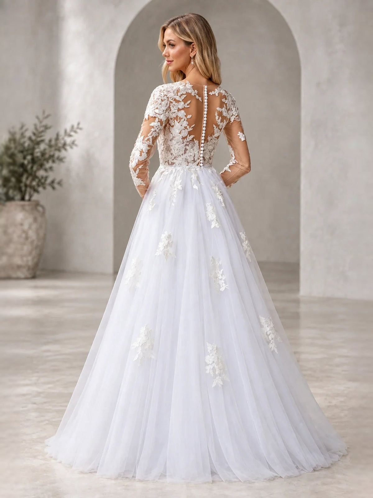 White A-line wedding dress seen from back with floral lace applique and long sleeves