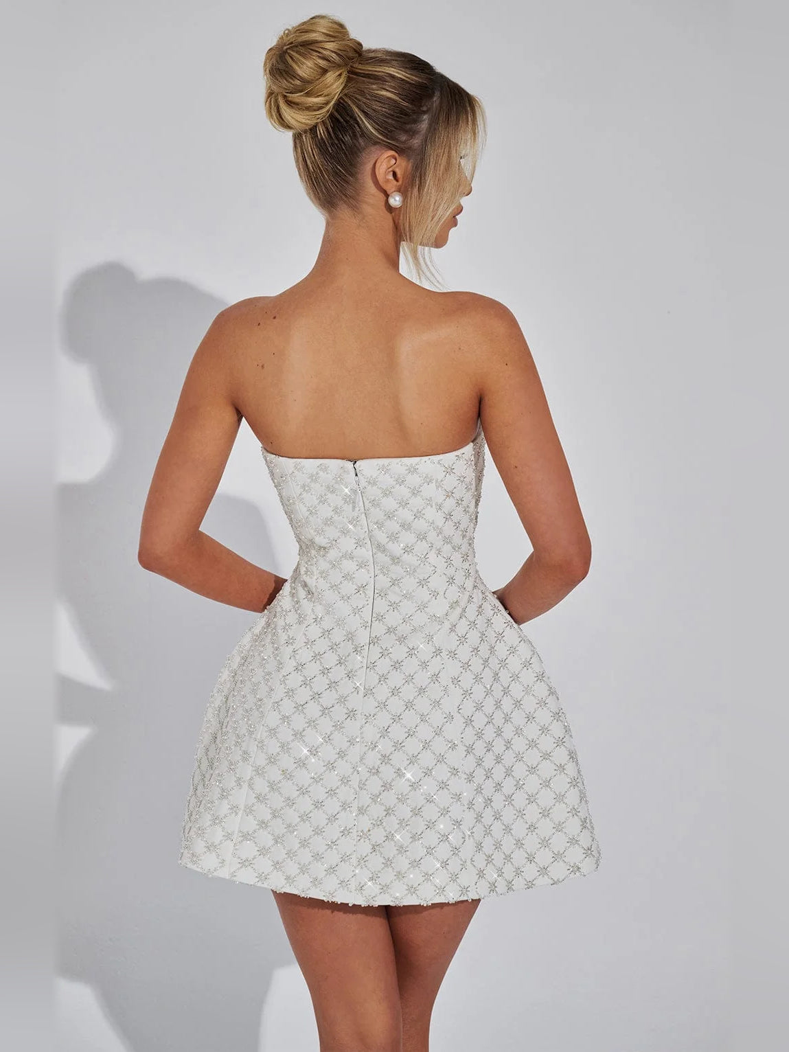 Ivory strapless mini dress shown from back, textured fabric with seam detailing and flared skirt.