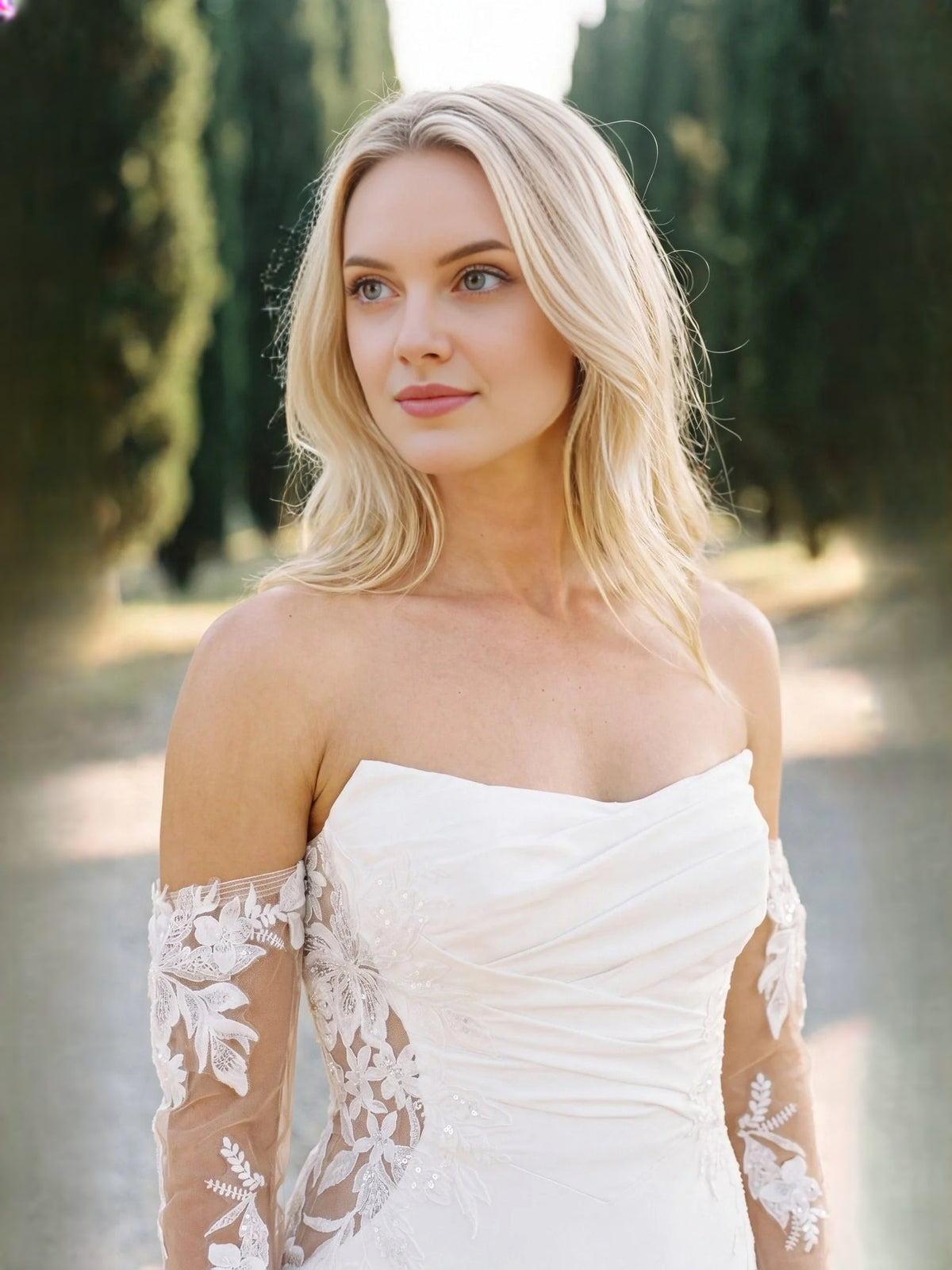 Close-up of ivory strapless wedding dress with ruched bodice and floral lace sleeves