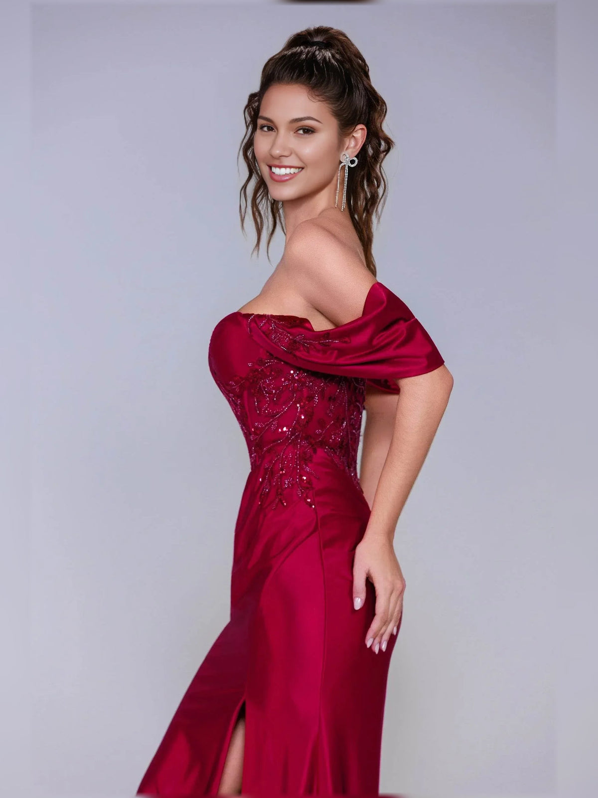 Deep red off-shoulder formal dress with draped sleeves, beaded bodice, and side slit.