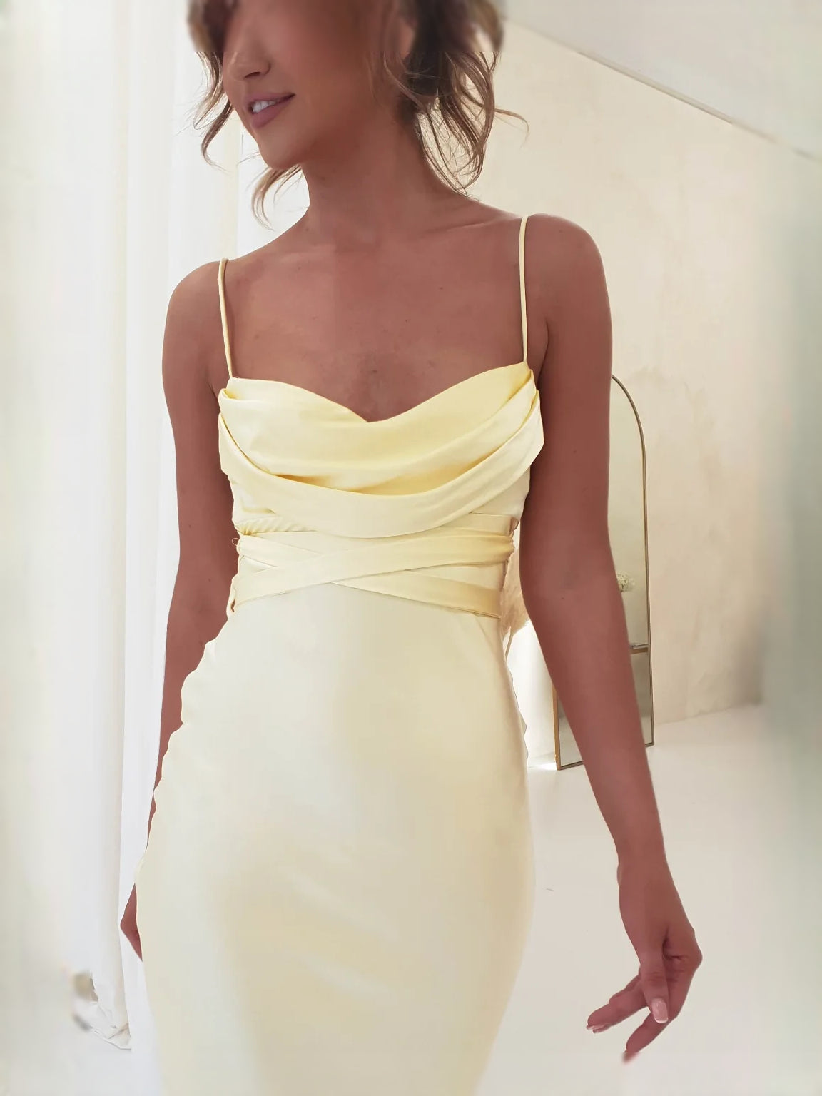 Close-up of yellow satin mermaid dress neckline with draped bodice and spaghetti straps