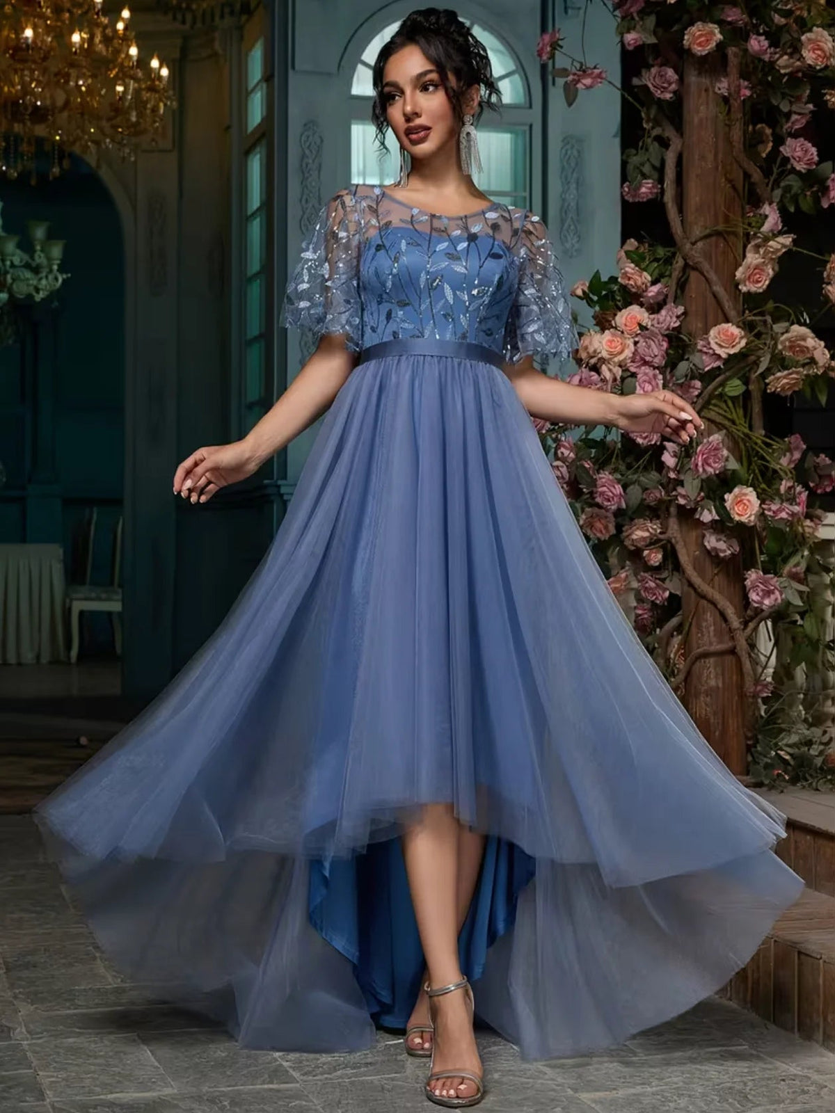Slate blue A-line maxi prom dress with embroidered bodice, ruffled sleeves, and asymmetric tulle hem.