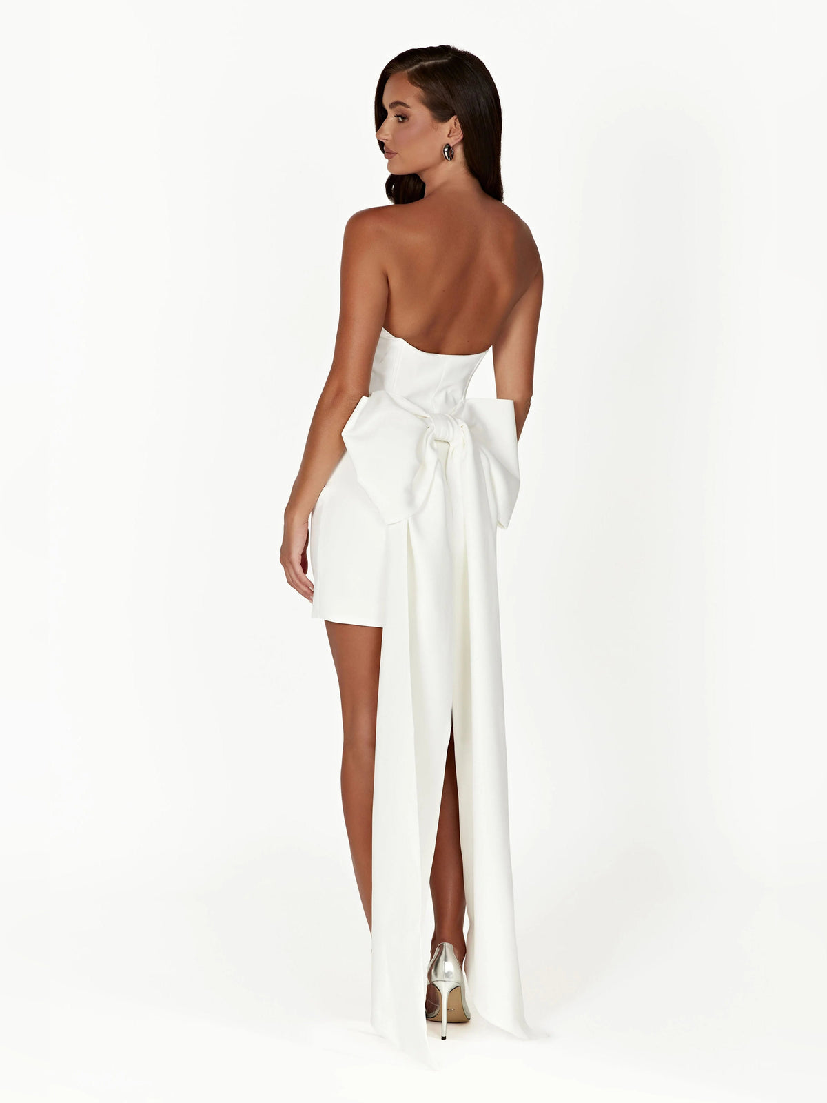 Back view of white strapless mini dress with bow detail and long flowing sash