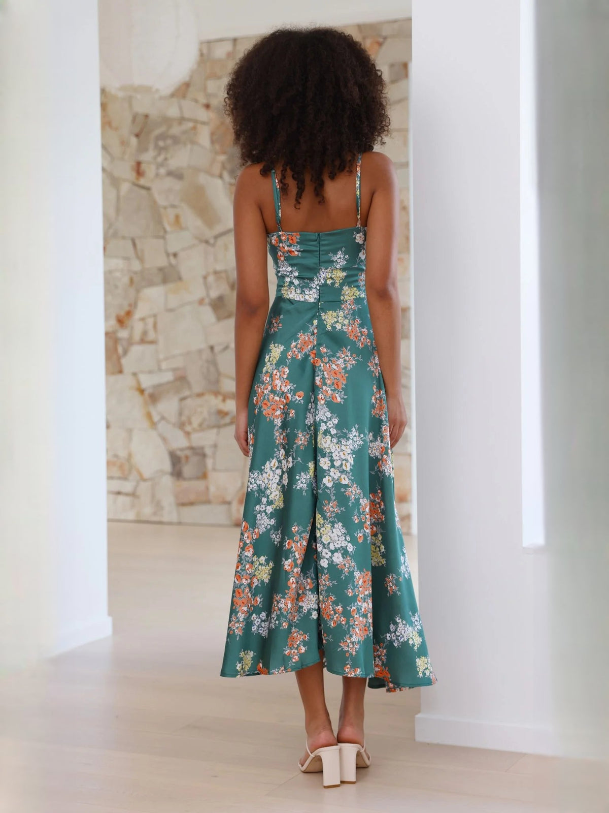 Back view of green floral midi dress with spaghetti straps and tied waist