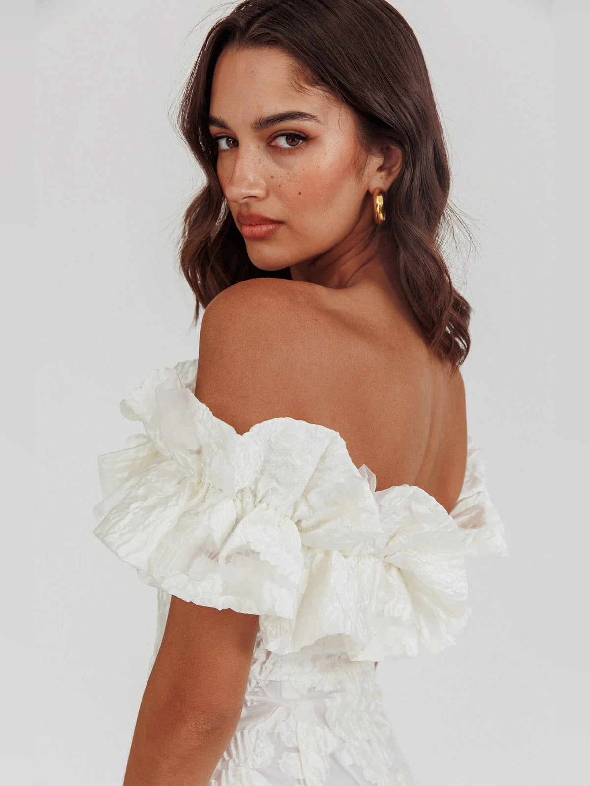 White off-shoulder mini dress with layered ruffle neckline and textured detail close-up