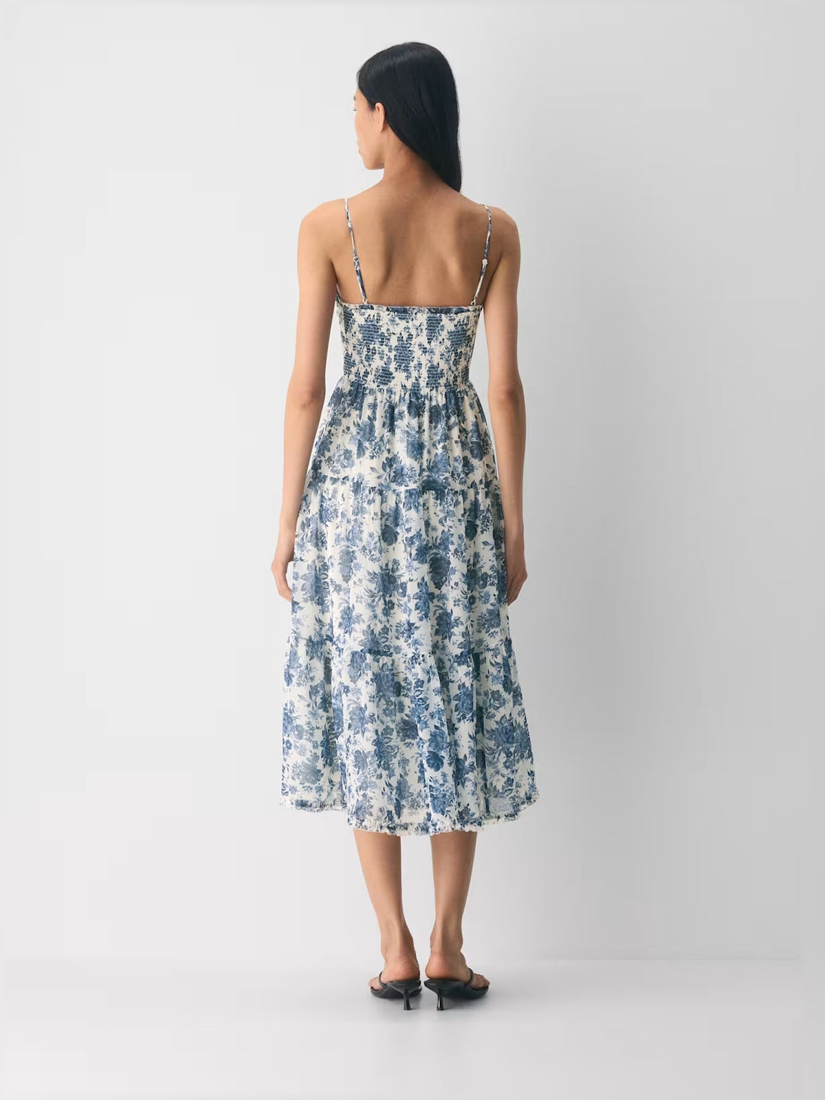Back view of blue floral tiered midi dress with spaghetti straps and layered skirt