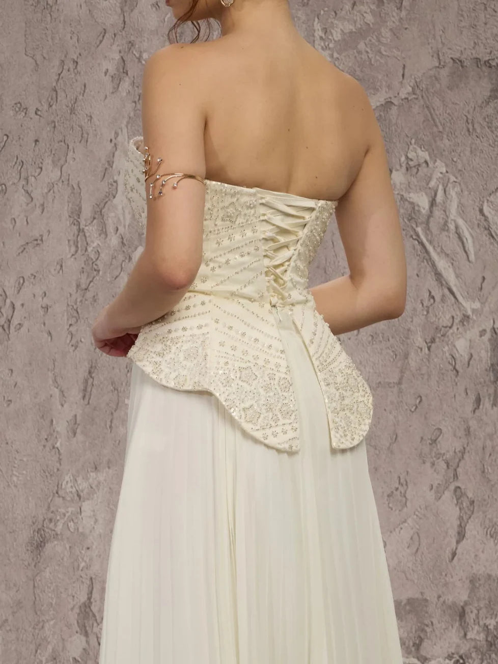 Cream corset peplum formal dress with lace back detailing and pleated chiffon skirt