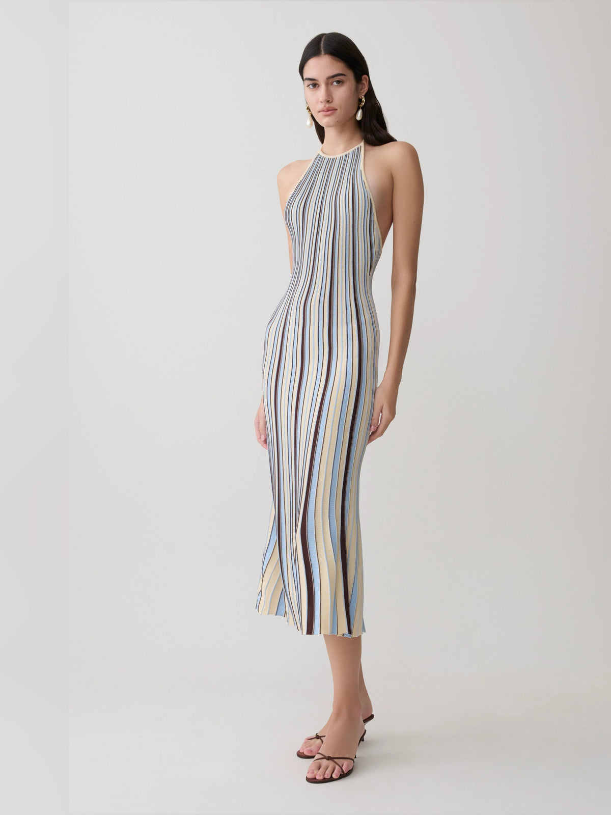 Side view of halterneck knit midi formal dress with vertical cream, blue, and brown stripes.