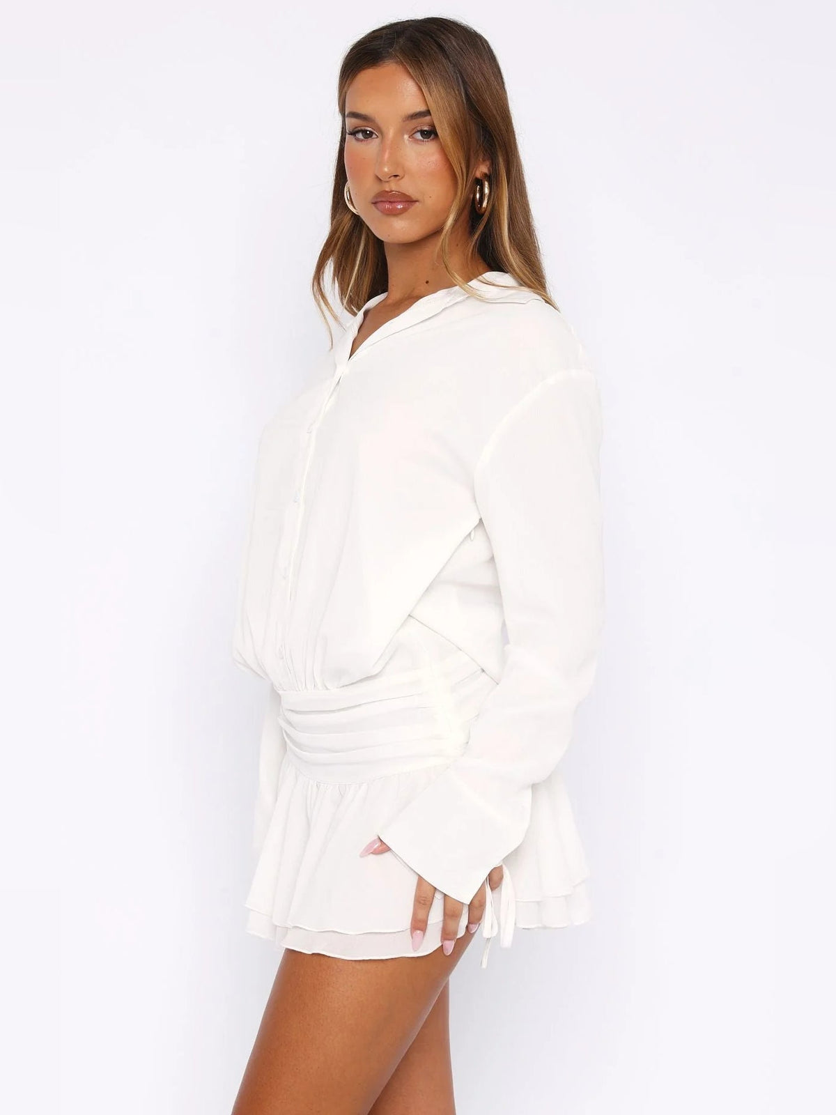 White long-sleeve mini dress from the side with deep V-neck and ruffled hem