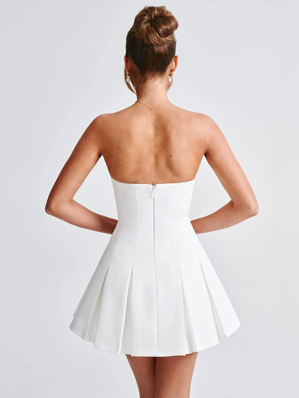 Ivory strapless mini dress viewed from back, with fitted back and pleated skirt