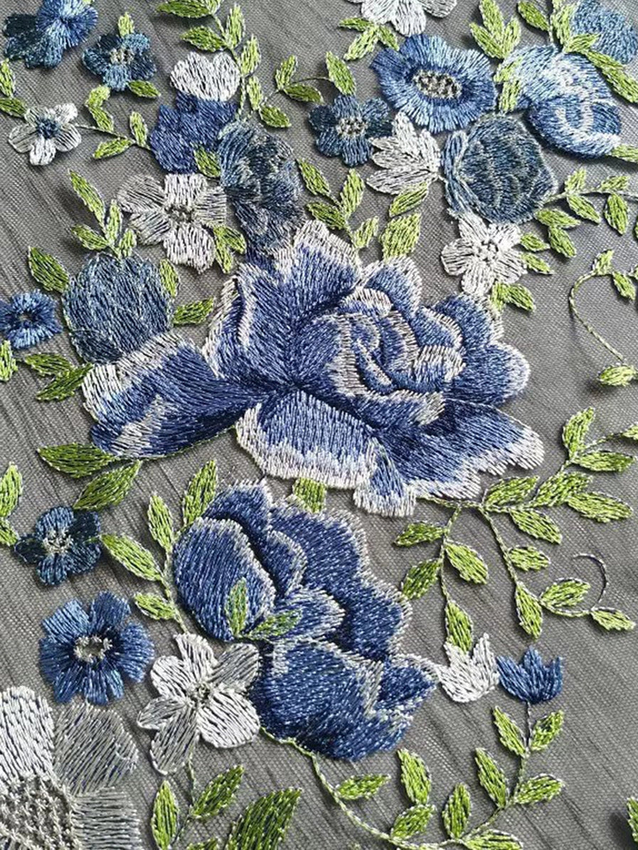 Light gray tulle with dense blue floral embroidery and green leaf accents